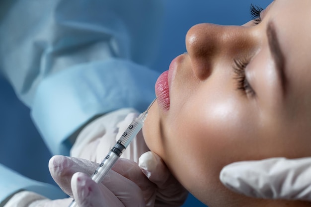 Handen van schoonheidsspecialist die injectie in gezichtslippen maakt jonge vrouw krijgt schoonheidsgezichtsinjecties in sa
