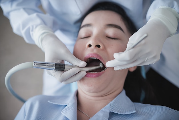 Handen van tandarts die een tandhulpmiddel houdt. De tanden controleren op de vrouw