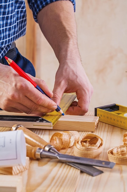 Handen van timmerman tekenen met potlood op houten planken bouwconcept
