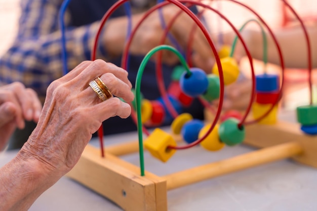 Foto handen van twee bejaarden die in de tuin van een verzorgingstehuis of bejaardentehuis spelen met spelletjes om de mobiliteit van de handen te verbeteren