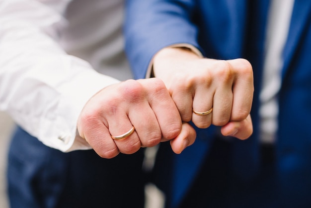 Handen van twee mannen met gouden trouwringen