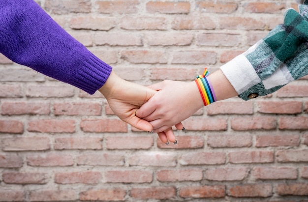 Handen van twee vrouwen met regenboogarmband gay pride