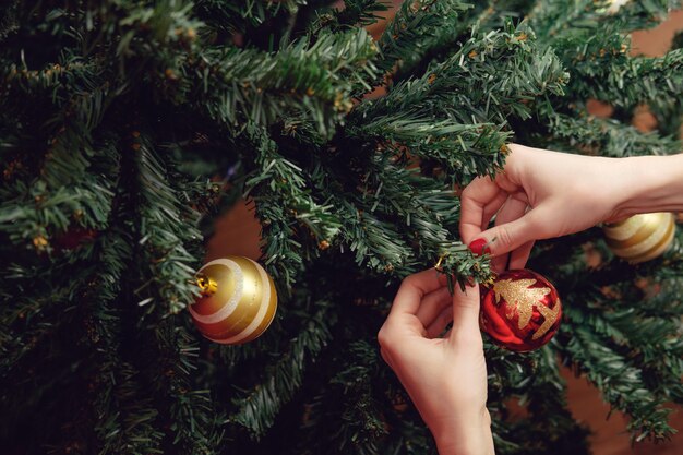 Handen van vrouw die Kerstmisboom verfraaien