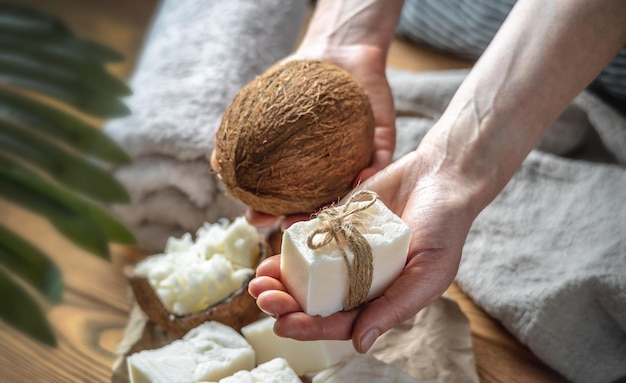 Handen van vrouw houden een stuk witte handgemaakte kokoszeep en verse kokosnoot Concept van het maken en gebruiken van natuurlijke zeep en eco-cosmetica een interessante creatieve hobby