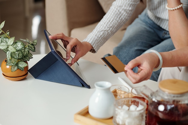 Handen van vrouw zoomen afbeelding op tabletcomputer bij het invoeren van informatie van creditcard