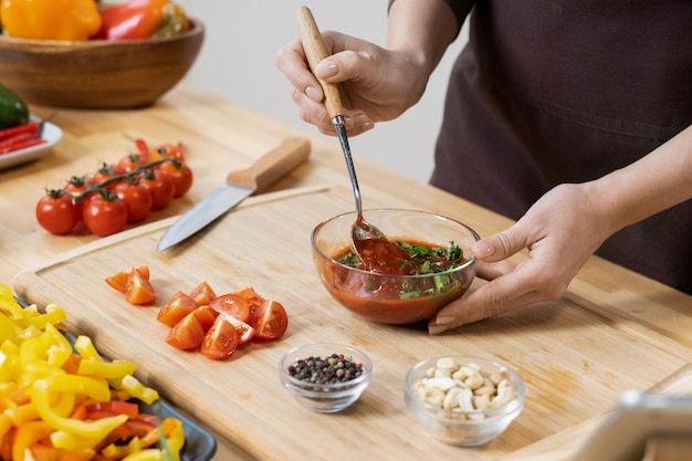 Handen van vrouwen die zelfgemaakte ketchup mengen met peterseliebladeren