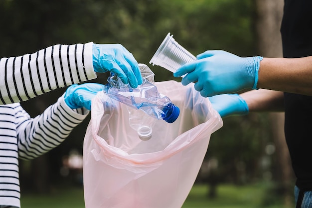 Handen van vrouwen en mannen verzamelen plastic afval voor reiniging in het park