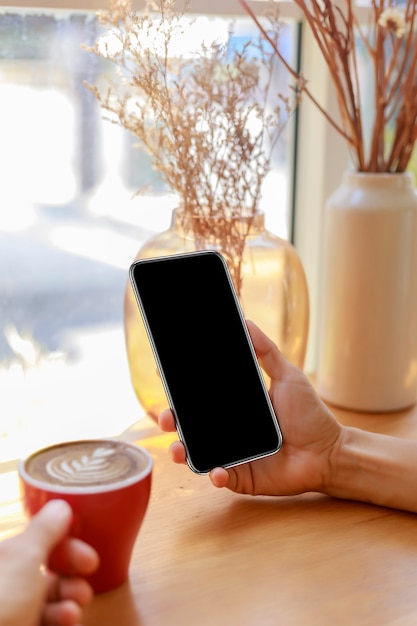 Handen van vrouwen met lege lege scherm slimme telefoon in café.