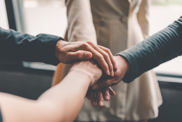 Handen van zakenmensen komen samen in een stapel handen om samenwerking, teamwork te symboliseren om doelen en succes te bereiken.