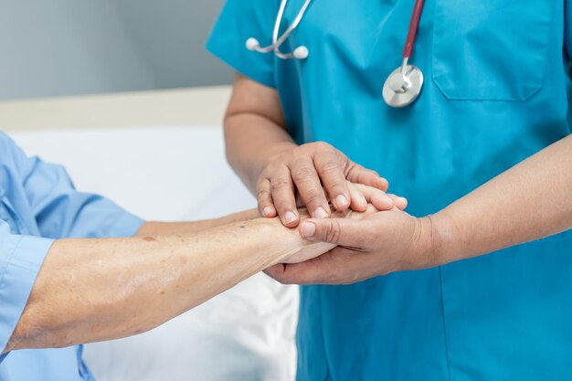 Handen vasthouden Aziatische senior of bejaarde oude dame vrouw patiënt met liefde zorg aanmoedigen en empathie op verpleeghuis afdeling gezond sterk medisch concept