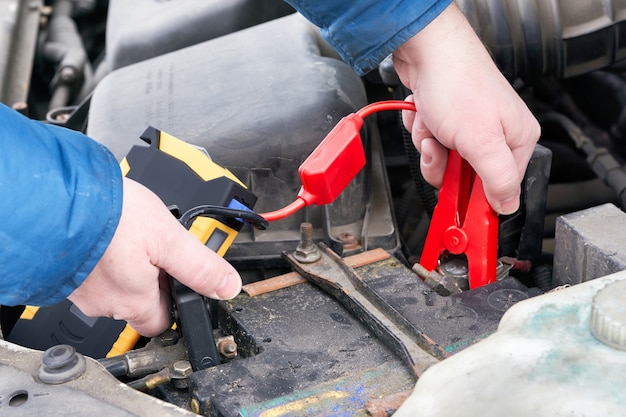 Handen verbinden de auto launcher met de batterij