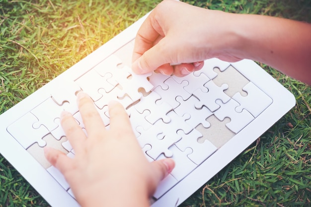 handen verbindende puzzelstukjes op groen gras achtergrond