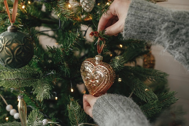 Handen versieren kerstboom met stijlvolle vintage kerstbal in feestelijke kamer Merry Christmas