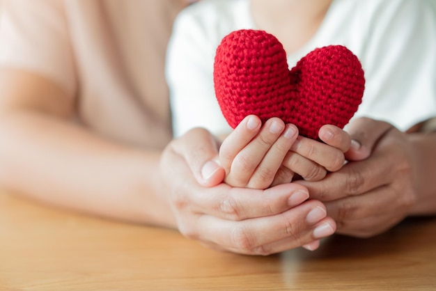 Handen voor volwassenen en kinderen met een garen rood hart Hoop liefde leven concept