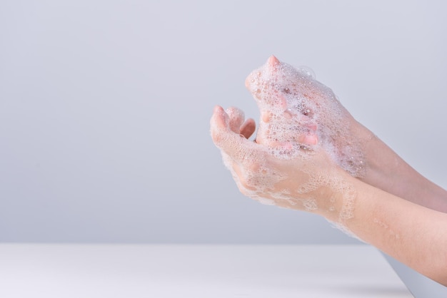 Handen wassen Aziatische jonge vrouw die vloeibare zeep gebruikt om handen te wassen concept van hygiëne tot beschermend pandemisch coronavirus geïsoleerd op een grijze witte achtergrond close-up
