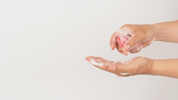 Foto handen wassen met schuim en roze zeep op witte achtergrond