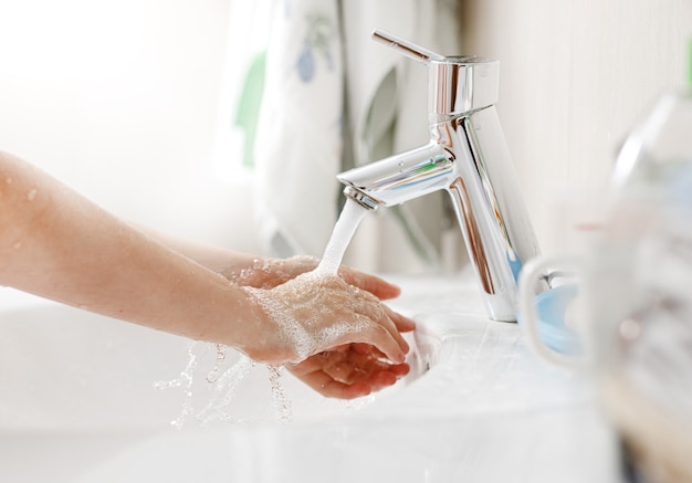 Handen wassen met zeep. Kind handen in een badkamer schoonmaken.