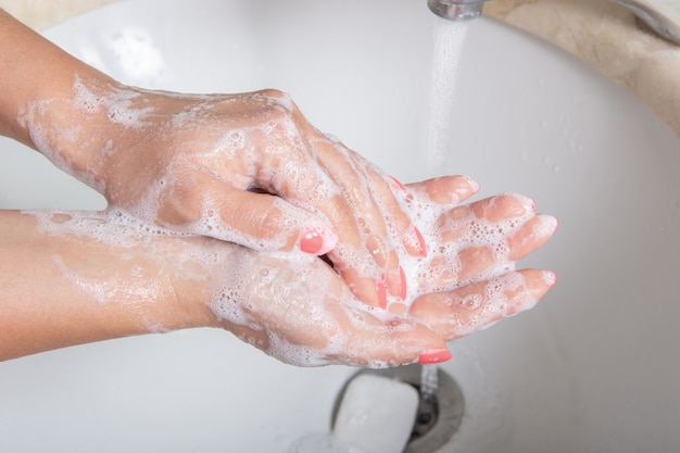 Handen wassen met zeep onder de kraan