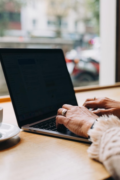 Handen werken aan een laptop op een houten tafel