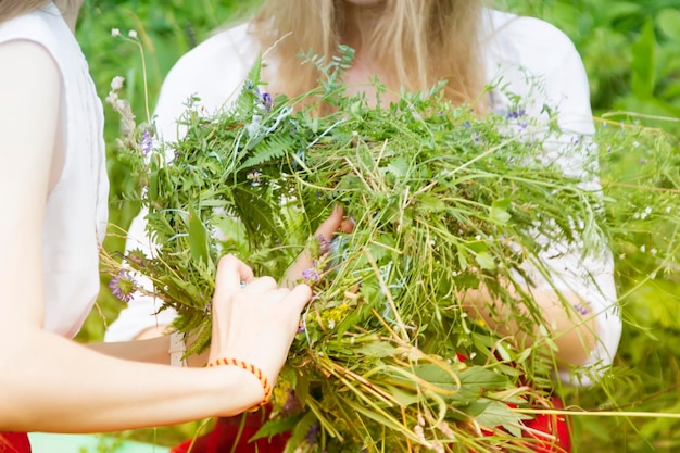 Handen weven een krans van wilde bloemen en kruiden