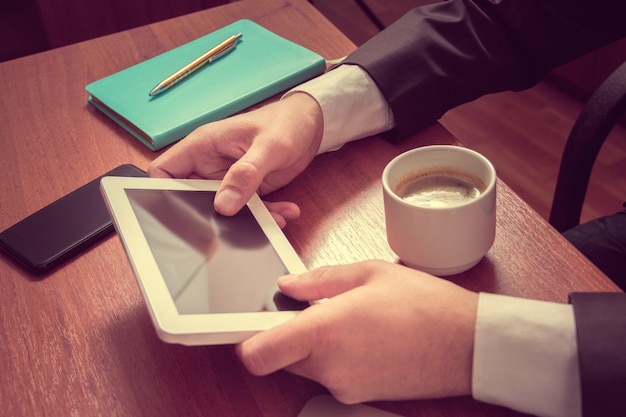 Handen zakenman op een tablet en koffie met laptop