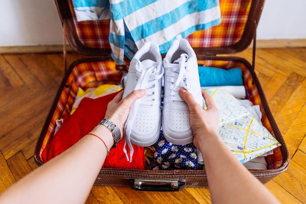 Handen zetten sneakers om de verpakking voor het reisreisconcept te valideren