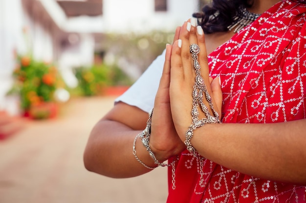 Handen zilveren armband ring sieraden gebaar namaste close-up Indiase vrouw in traditionele sari rode jurk bidden in hindoe tempel goa india hindoeïsme meisje katholicisme Delhi om yoga meditatie vrouwelijk model