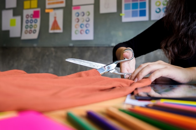 Handenklem op maat van de kleermaker&#39;s schaardoekje snijden een stuk stof (modeontwerperconcept).