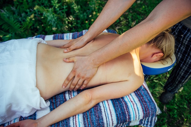 Handenmasseur op de rug van een onherkenbaar geduldig close-up. De ontspannen vrouw ontvangt wellnessmassage in het Kuuroord openlucht.