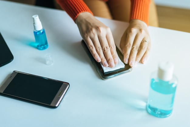 Handenvrouw die vuile mobiele telefoon op het scherm schoonmaken, Preventieve maatregelen tegen coronavirus