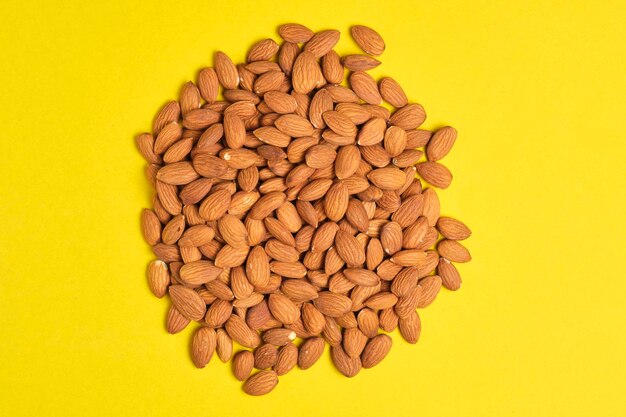 Photo handful of almonds yellow background