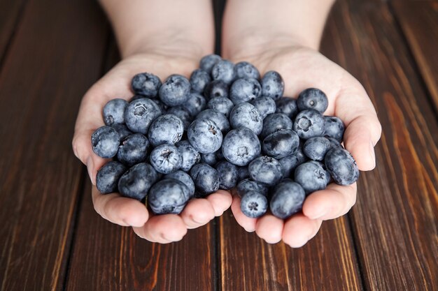 A handful of blueberries on brown wooden background closeup