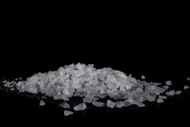 A handful of coarse sea salt on a black background.