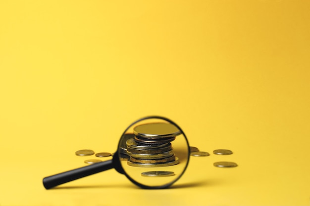 A handful of coins in a magnifying glass. Black magnifying glass magnifies coins.