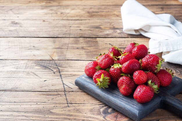 Handful Juicy ripe strawberries on a wooden rustic background. Sweet healthy dessert, vitamin harvest. copy space.