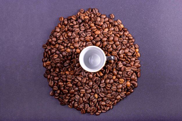 Handful of natural coffee beans with a cup in the center International Coffee Day concept October 1st