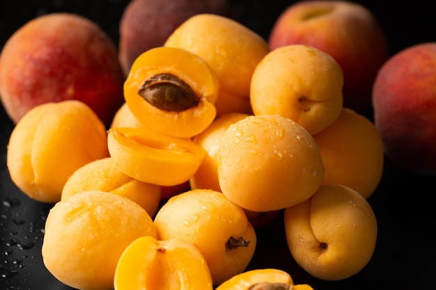 A handful of ripe raw apricots on a dark background