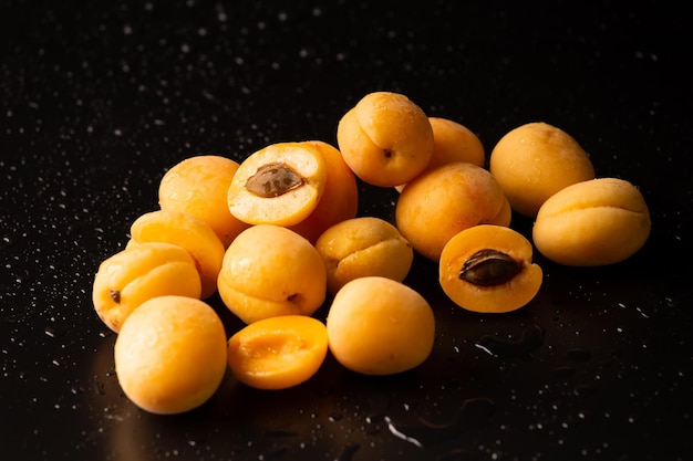 A handful of ripe raw apricots on a dark background