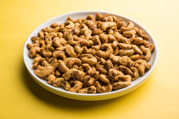 A handful roasted spiced cashew nuts  or masala kaju served in a bowl, selective focus