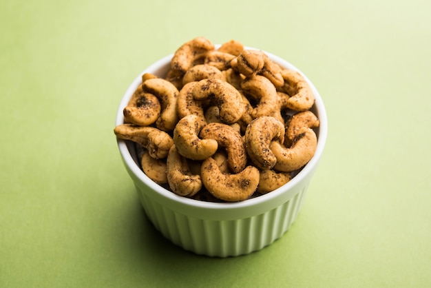 A handful roasted spiced cashew nuts  or masala kaju served in a bowl, selective focus