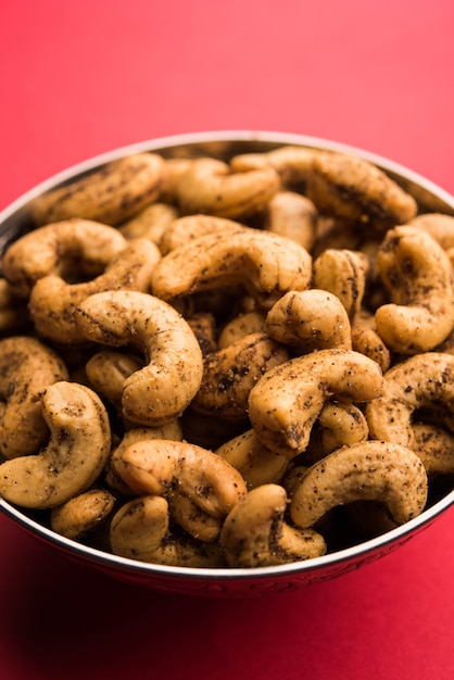 A handful roasted spiced cashew nuts  or masala kaju served in a bowl, selective focus