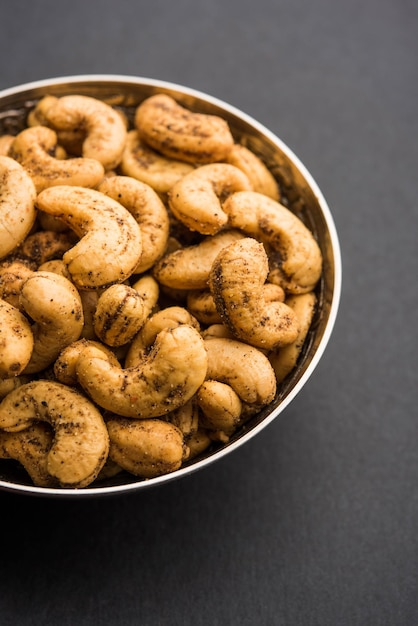 A handful roasted spiced cashew nuts  or masala kaju served in a bowl, selective focus