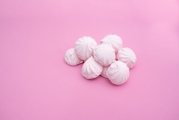 Handful of small marshmallows on a pink background