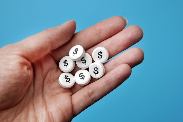 A handful of white pills with a dollar sign . a symbol of\
expensive treatment