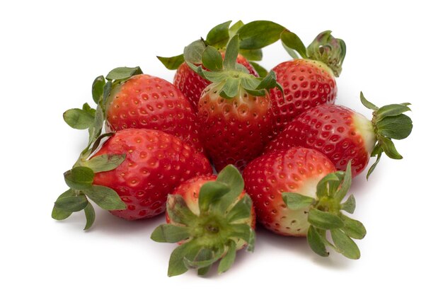 A handful of whole strawberries with their green leaves laid out in a star shape. Isolated on white 