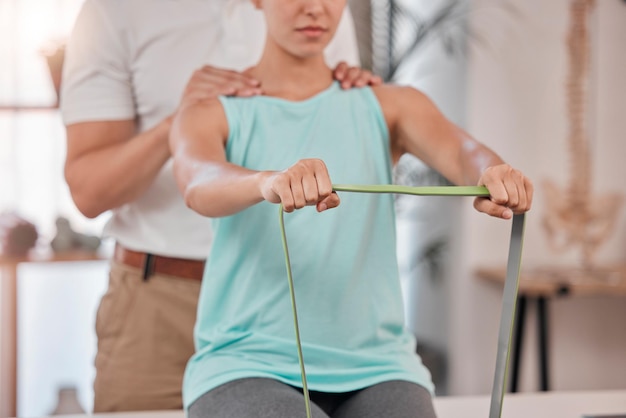 Handfysiotherapie en revalidatie met een vrouw die een weerstandsband uitrekt tijdens een sessie in een kliniek Fitnessadviseur en revalidatie met een vrouwelijke patiënt en fysio in een kantoor voor herstel