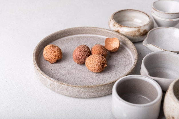 Handgemaakt keramisch servies, leeg ambachtelijk keramiek op een lichte achtergrond. Borden en kopjes van klei