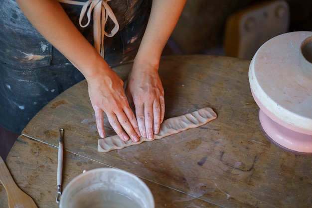 Handgemaakte aardewerk creatie vrouwelijke ambachtsvrouw handen werken met natte klei op houten tafel in studio