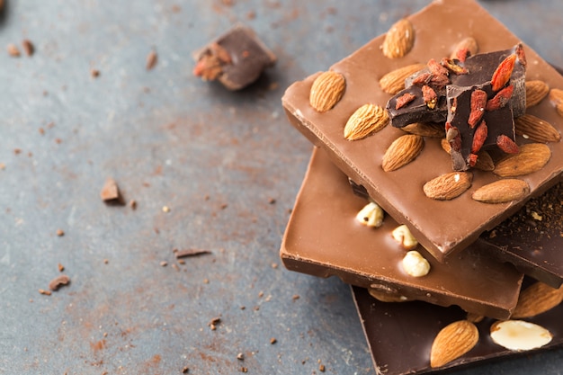 Handgemaakte chocoladerepen met noten en gojibes op een grijs