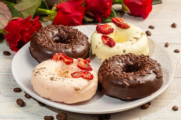 Handgemaakte donuts op een lichte achtergrond in witte en zwarte chocolade. Er zijn bloemen in de buurt. Vrouwendag, Valentijnsdag.